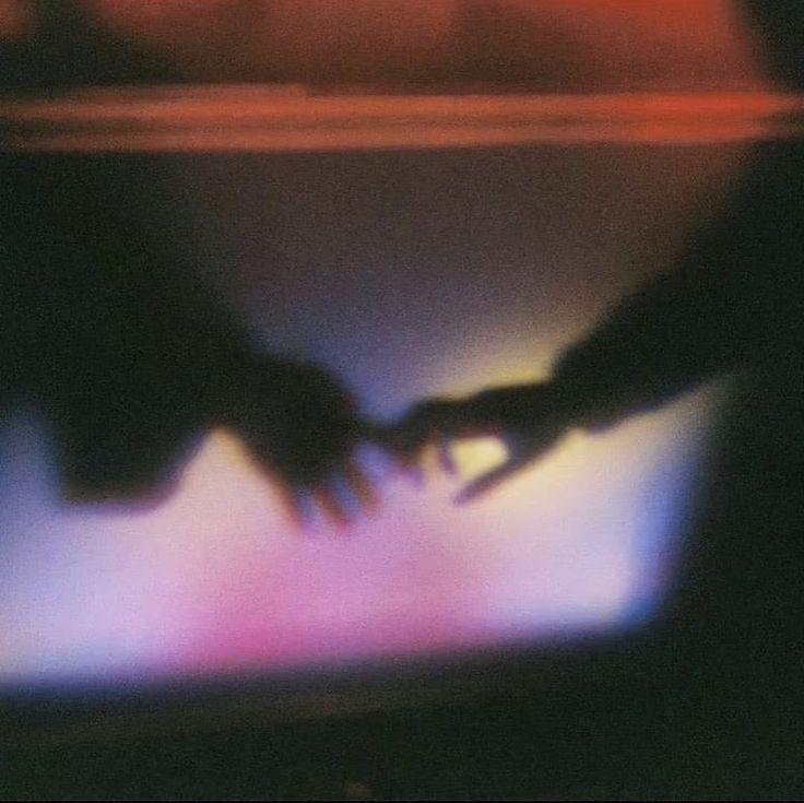 A dreamy, dark scene of two hands almost touching